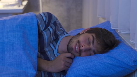 Young-man-sleeping-in-his-bed-having-good-dreams-and-smiling.-Happy-Sleep.